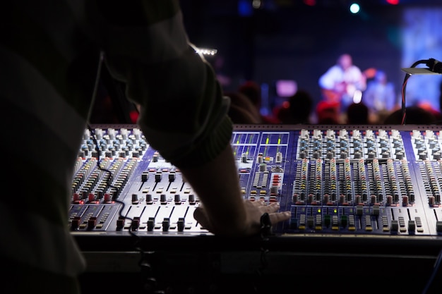 Soundman travaillant sur la console de mixage. Les mains sur les curseurs.