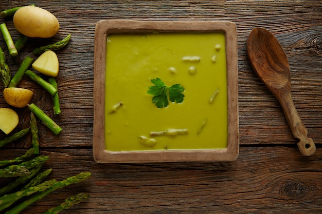 Soupe d&#39;asperges vert crème sur une table en bois vieilli