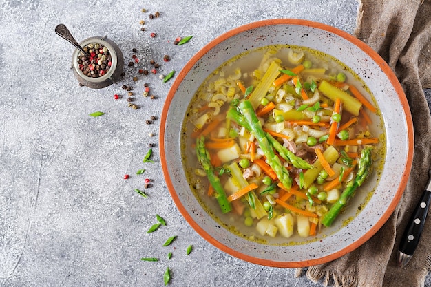 Soupe au bœuf, asperges, pois verts, carottes et céleri. Vue de dessus.