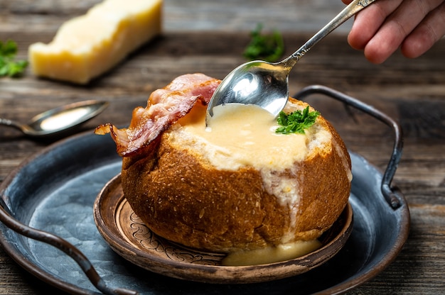 Photo soupe au fromage avec bacon et herbes servie dans du pain