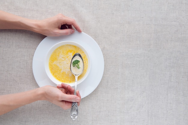 Soupe au fromage avec brocoli dans une assiette blanche sur une nappe en lin blanc