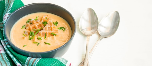 Soupe au fromage avec craquelins et herbes. Soupe à la crème sur une table en bois clair. Espace de copie.