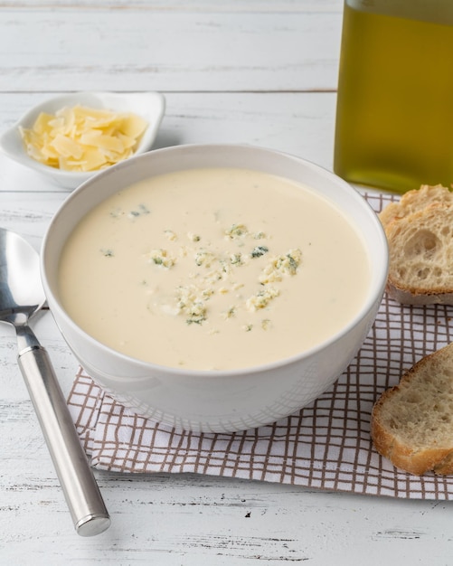 Soupe au fromage dans un bol avec des tranches de pain et des assaisonnements sur une table en bois