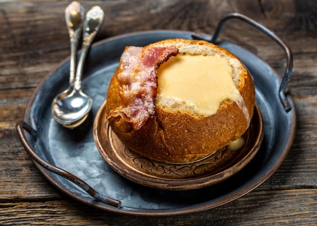 Soupe au fromage avec du bacon et des herbes servies dans du pain sur fond de bois Menu du restaurant recette de livre de régime