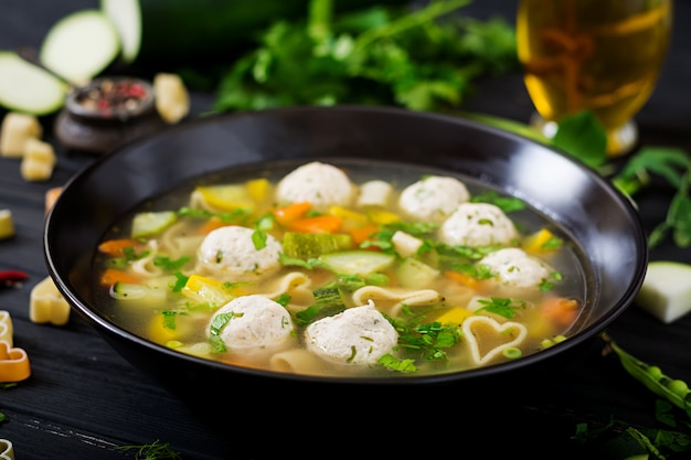 Soupe au poulet et aux légumes avec boulettes de viande, courgettes et pâtes.