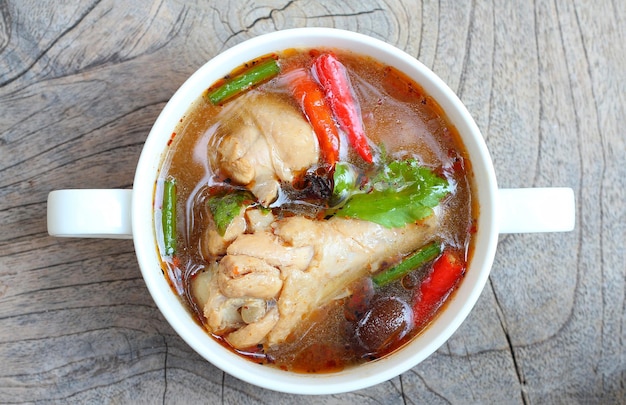 Soupe au poulet cuisine thaïlandaise préférée chaude et épicée dans un bol blanc sur une table en bois