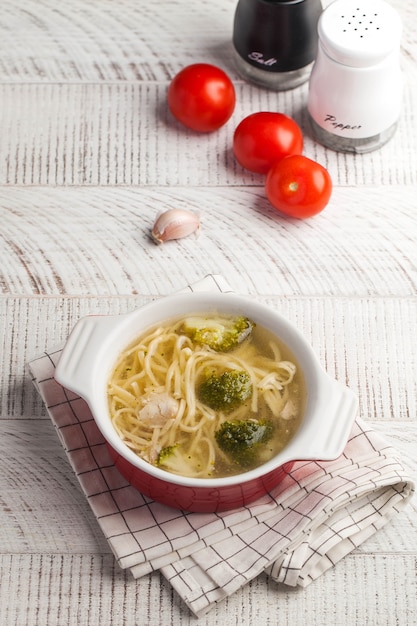 Soupe au poulet maison avec des nouilles et des légumes sur une table en bois