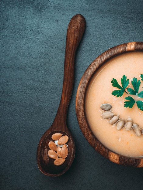 Soupe d'automne à la citrouille dans un bol en bois avec des graines de persil nourriture végétalienne de légumes diététiques