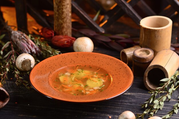 Soupe aux champignons et carottes. sur une table en bois noire avec décor