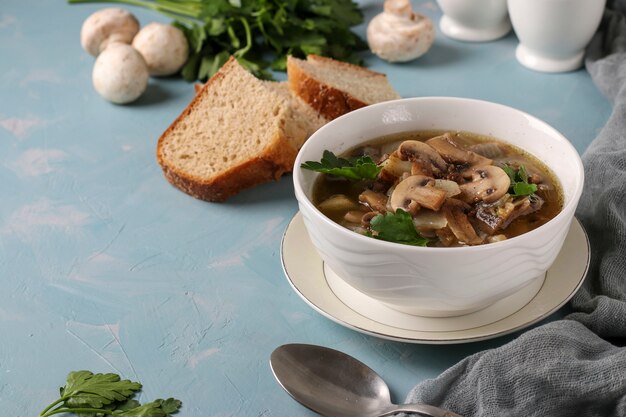 Soupe aux champignons de champignons et lentilles dans une assiette blanche sur une surface bleu clair, espace copie