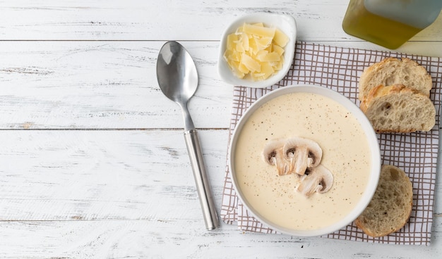 Soupe aux champignons dans un bol avec des tranches de pain et des assaisonnements sur une table en bois avec espace de copie