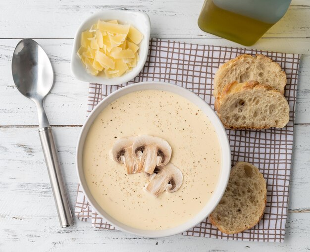 Soupe aux champignons dans un bol avec des tranches de pain et des assaisonnements sur une table en bois