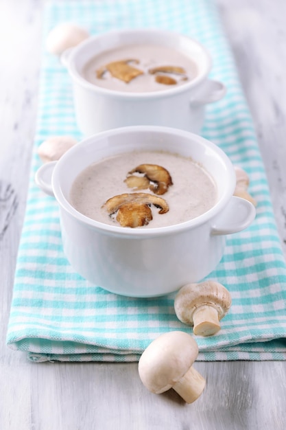 Soupe aux champignons dans des pots blancs sur une serviette sur fond de bois