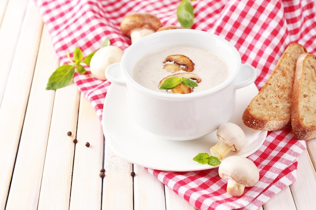 Soupe aux champignons en pot blanc sur serviette sur fond de bois