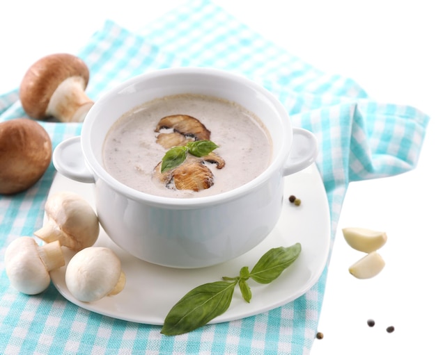 Soupe aux champignons en pot blanc sur serviette isolé sur blanc