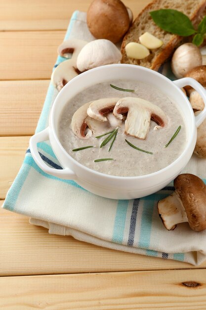 Soupe aux champignons en pot sur une serviette de couleur sur fond de bois