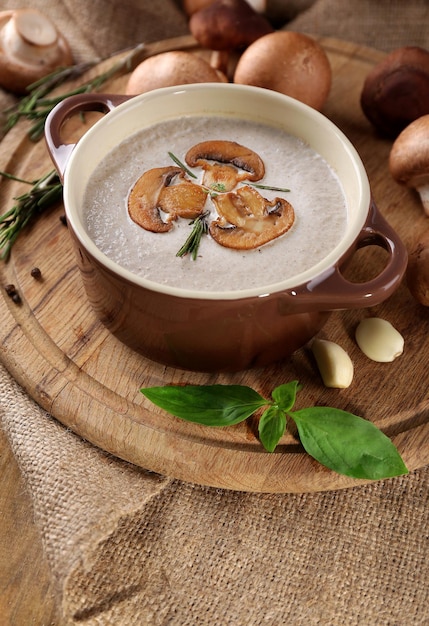 Soupe aux champignons en pot sur serviette sur fond de bois