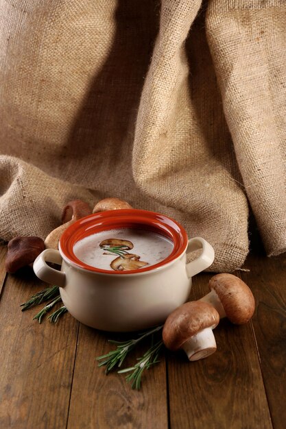 Soupe aux champignons en pot sur table en bois sur fond d'un sac