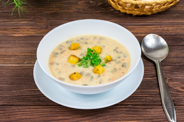 Soupe aux champignons végétarienne faite maison avec des légumes et du pain dans une assiette blanche