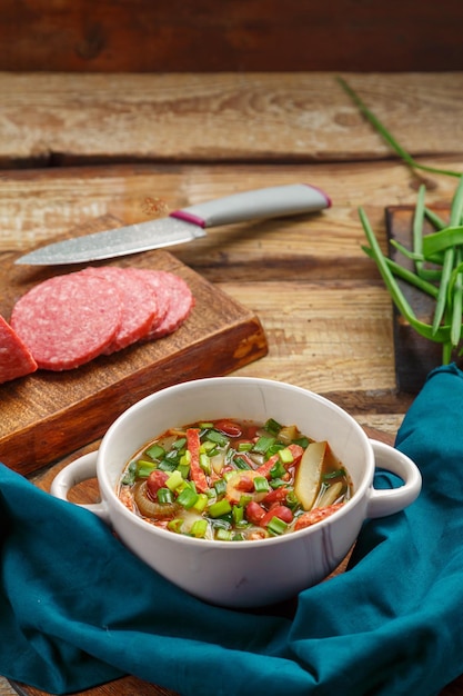 Soupe aux haricots de cuisine juive cholit sur un oignon de saucisse de serviette bleue et une cuillère en bois à proximité