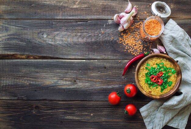 Soupe aux lentilles maison dans un bol avec des ingrédients sur fond de bois rustique Nourriture végétarienne saine