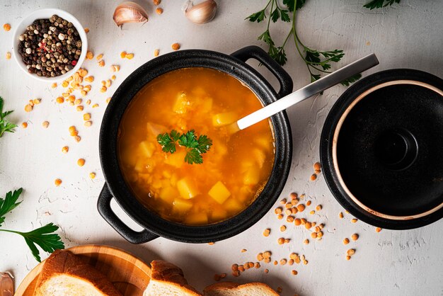 Soupe aux pois sur fond clair. Soupe dans une casserole noire. Un bol de soupe. Persil, mélange de poivre, sauce, pain. photo de haute qualité