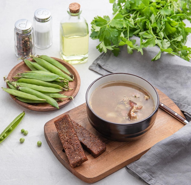 Soupe aux pois avec de la viande fumée à Minsk sur une planche de bois avec croûtons légumes frais herbes et épices