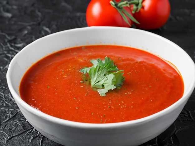 Soupe aux tomates dans un bol en céramique sur fond sombre