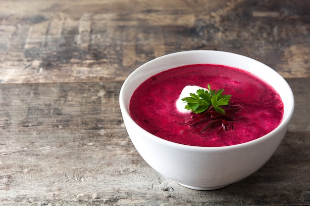 Soupe de betteraves dans un bol blanc sur l'espace de copie de table en bois