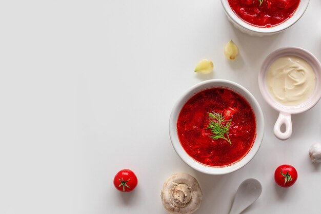 Soupe de betteraves ukrainienne traditionnelle faite maison avec de l'aneth vert frais. Bortsch russe dans un bol de tomates, crème sure et champignons sur fond blanc avec copie espace.