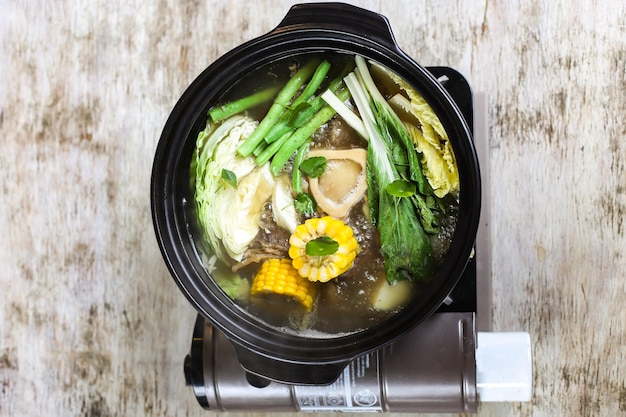 Soupe Bulalo à la moelle osseuse avec maïs et légumes servis dans un bol isolé sur fond gris vue latérale de compote