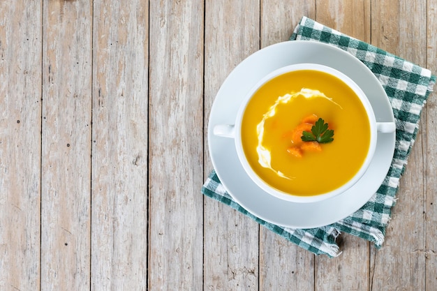 Soupe de carottes à la crème et persil sur table en bois