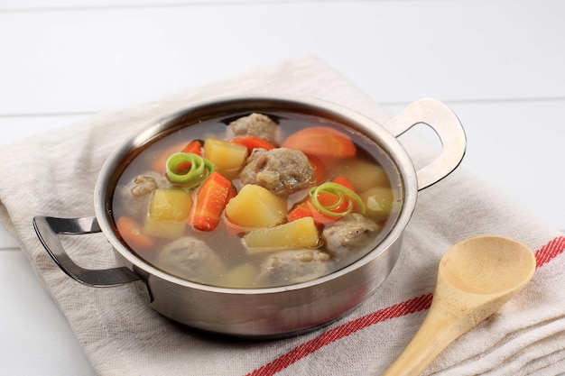 Soupe chaude faite maison aux boulettes de viande aux légumes avec carottes et pommes de terre servie dans un bol en acier inoxydable