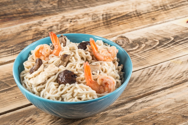 Soupe chinoise avec nouilles udon, porc, œufs durs, champignons et crevettes en gros plan dans un bol sur la table