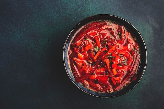 Soupe de chou rouge maison traditionnelle avec betteraves, légumes et herbes Bortsch russe dans une assiette sur fond de table de cuisine bleu vue de dessus copie espace Végétalien végétarien régime alimentaire sain