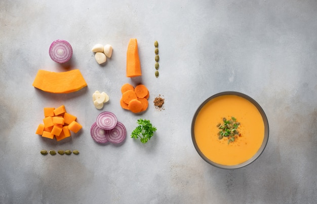 Soupe à la citrouille d'automne dans un bol et ingrédients pour la cuisson.