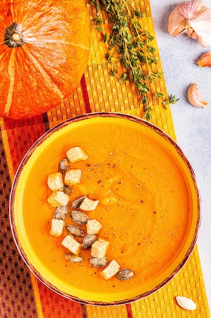 Soupe à la citrouille et aux carottes servie avec des graines, vue de dessus.