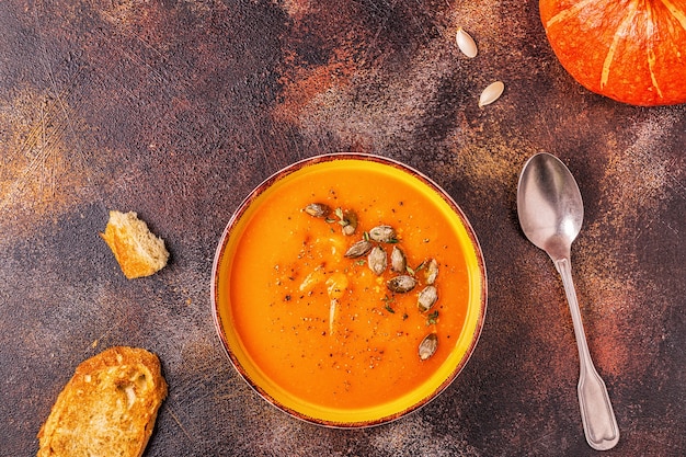 Soupe à la citrouille et aux carottes servie avec des graines, vue de dessus.