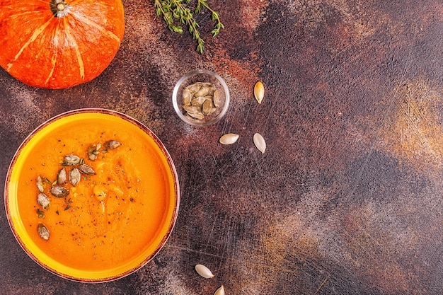 Soupe à la citrouille et aux carottes servie avec des graines, vue de dessus.