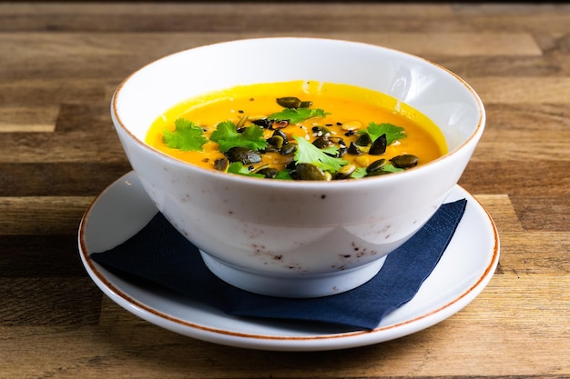 Soupe de citrouille et de carotte avec de la crème et du persil sur fond de bois sombre