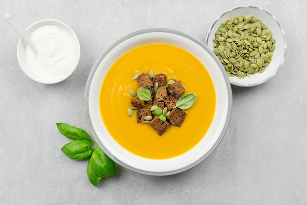 Soupe de citrouille et de carottes rôties d'automne de saison avec croûtons de pain à la crème et au seigle sur fond de béton clair Vue de dessus