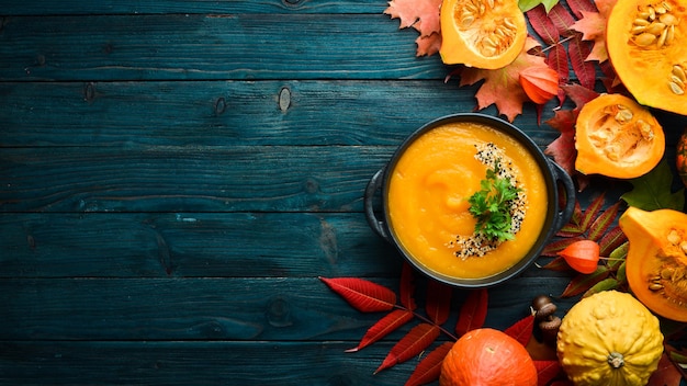 Soupe à la citrouille avec citrouille et feuilles d'automne colorées à plat Sur un fond en bois bleu Vue de dessus Espace libre pour votre texte