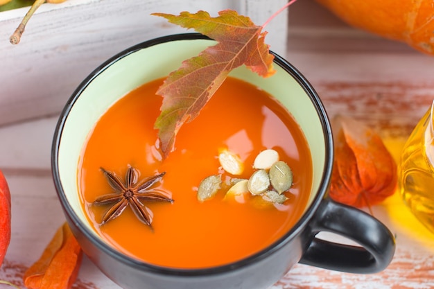 Soupe à la citrouille avec de la crème et des graines de citrouille et un seau sur un fond en bois blanc Copier l'espace