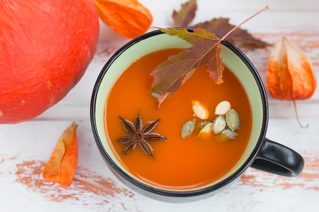 Soupe à la citrouille avec de la crème et des graines de citrouille et un seau sur un fond en bois blanc Copier l'espace