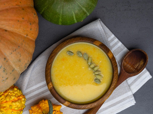 Soupe à la citrouille dans un bol en bois sur fond gris