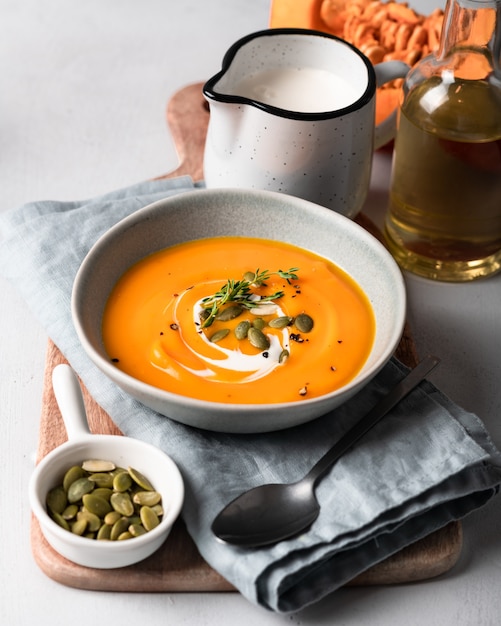 Soupe à la citrouille dans un bol en céramique sur une planche à découper en bois