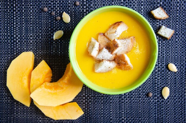 Soupe à la citrouille dans une tasse verte et des morceaux de citrouille