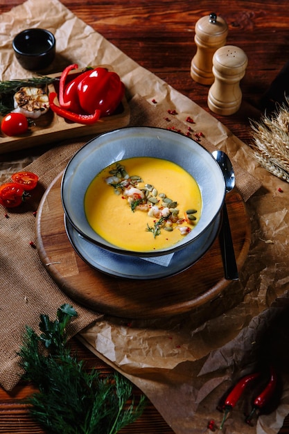 Soupe à la citrouille jaune dans une assiette en argile sur la table