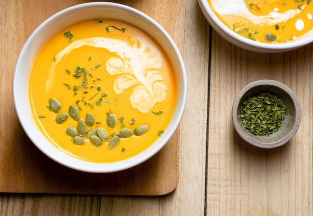 Soupe à la citrouille jaune avec des graines de citrouille à la crème et du persil sur fond de bois Espace de copie Vue de dessus