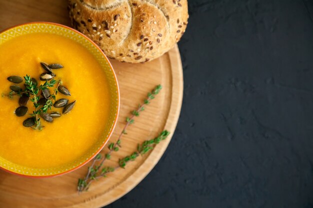 Soupe à la citrouille maison orange vif en gros plan, servie avec des graines